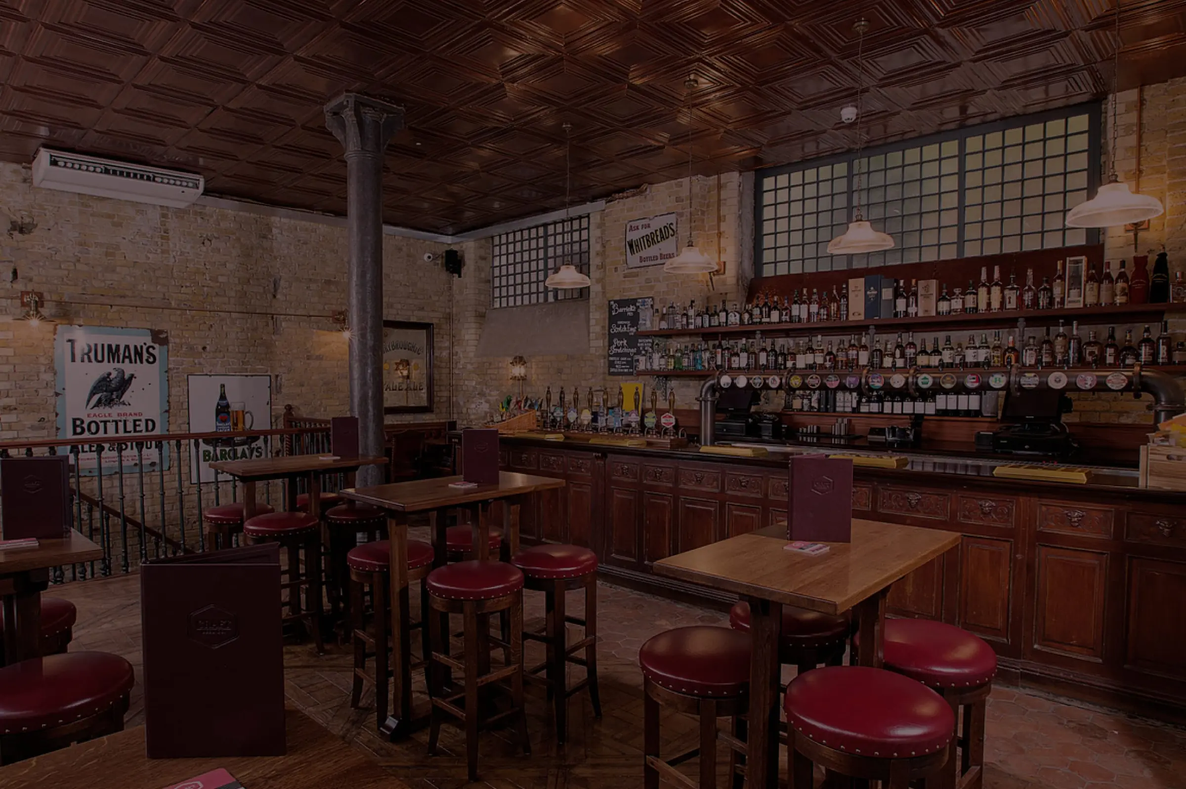 The main bar at The Catherine Eddowes, with red leather stools and a back bar of spirits
